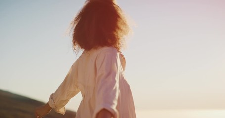 Young stylish carefree african american woman raising her arms joyfully at sunset embracing life to the fullest, happy smiling black woman expressing joy and contentment in her life - Powered by Adobe