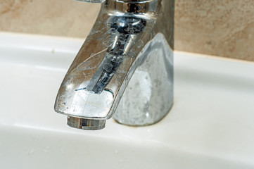 Stains from hard water on the chrome spout of the tap. Dirty sink faucet.