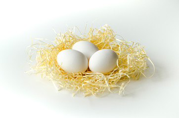 3 eggs on the straw on a white background