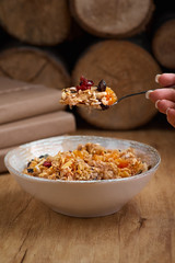 Healthy breakfast concept. Oatmeal, quinoa granola with yogurt, dried fruit, seeds, honey, persimmon in bowl over grey concrete background, top view, copy space. Allergy-friendly, gluten free concept