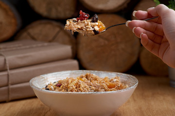 Healthy breakfast concept. Oatmeal, quinoa granola with yogurt, dried fruit, seeds, honey, persimmon in bowl over grey concrete background, top view, copy space. Allergy-friendly, gluten free concept