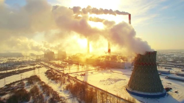 Aerial panoramic flight of hyperlaps around the thermal power plant. Winter carbon dioxide emissions, Energy of smoke and steam, sun shines through clouds of smoke. Ecology and pollution of nature.