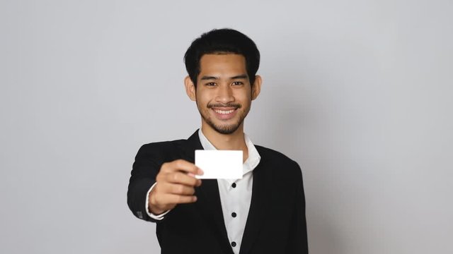 Smiling young asian business man showing business card.