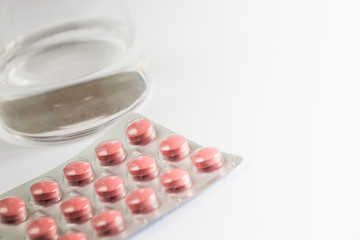 Pills capsules medicine and glass of water on white background