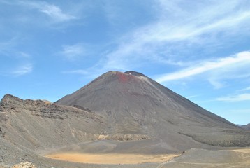 Fototapeta premium Vulcano with red crater on the Tangoriro Crossing tour, hiking in the mountains, blue sky, dry gravel land