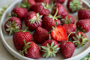 ripe juicy strawberries in a clay plate on a light background with copy space/