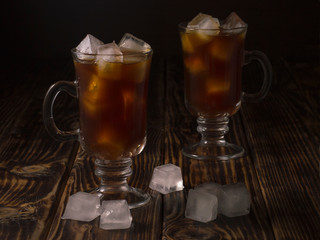 coffee drink with ice in a glass mug on a wooden background.