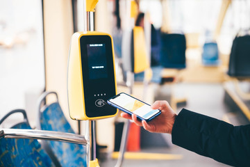 Girl paying conctactless phone for the tram ticket. Payment by card, Bank transfer .