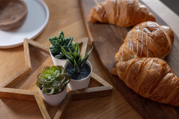 Three large croissants lie on a wooden board on the table.