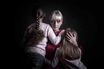 A woman puts her arms around her children trying to calm them down. The children are seven years old.