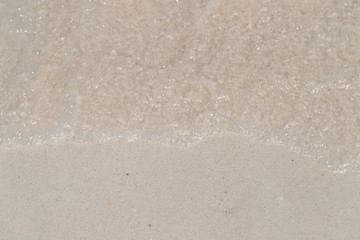 Top view of sea water on the clean white sand from wave ripple moving from top