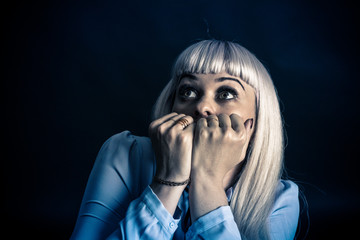 Portrait of a woman on a black background. The woman is blonde, dressed in a light blouse. Shows...
