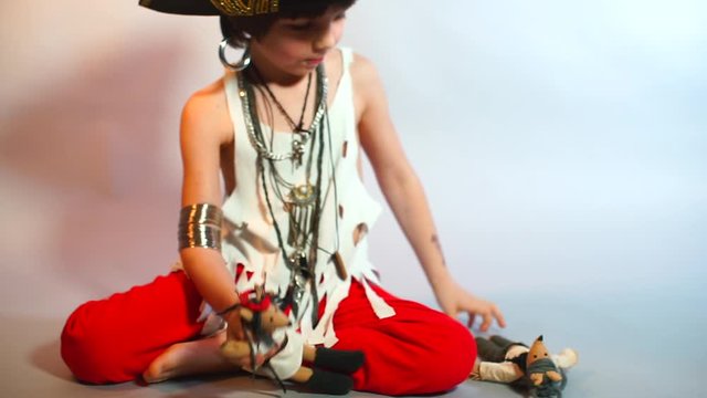 A child plays with pirate dolls on a white background in kindergarten.