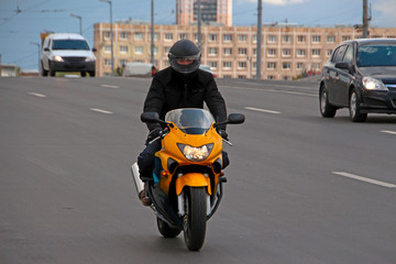 a man in a black helmet rides a yellow motorcycle on a speedway