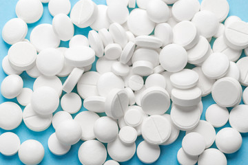 scattered white pills on a blue table. Layout for special offers such as advertising or other ideas. The concept of medicine, pharmacy and healthcare. Space for copy. flat lay for text or logo.