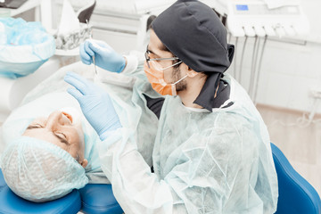 Patient and dentist during implant placement operation. Real operation. Tooth extraction, implants. Professional uniform and equipment of a dentist. Healthcare Equipping a doctor’s workplace. 