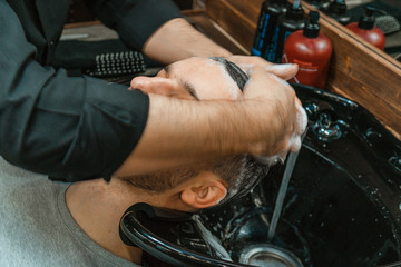 Obraz premium Barbershop, a man is washed his hair. Barber washes his client. Wash hair and beards after cutting. Personal care