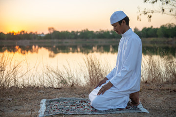 Silhouette Young asian muslim man praying on sunset,Ramadan festival concept