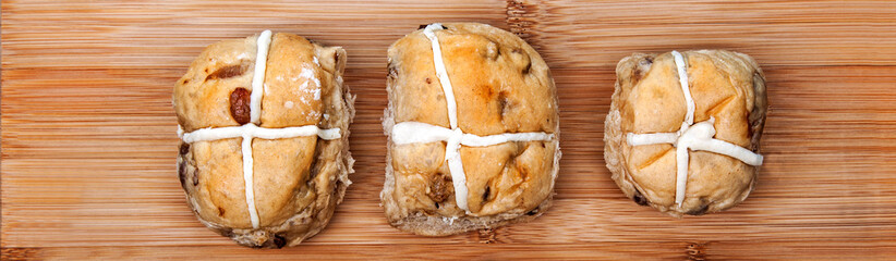 Hot cross buns on plain, rustic, wooden background - Easter banner / design / header / panorama.