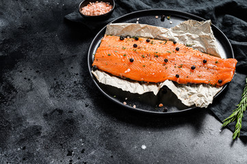 Fresh sea trout fillet with salt, herbs and spices. Black background. Top view. Copy space