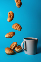 Croissants with chocolate filling and a cup of tea on the table on a bright blue background