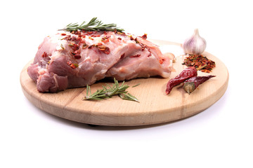 Pork tenderloin in one piece, rosemary, chili pepper, spices on a round wooden cutting Board on a white isolated background