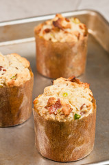 Front, top view, close up of three freshly baked sweet corn bacon, jalapeño muffins in their paper form, cooling on a baking sheet