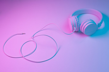 Retro 90s style photo of white stylish wireless headphone in neon lights. Music concept.