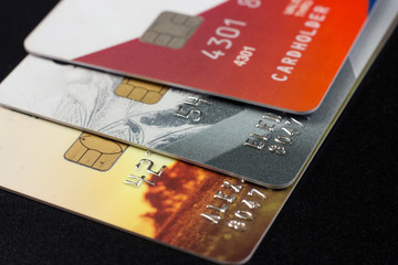 Three bank credit cards with chips of different colors on a black background