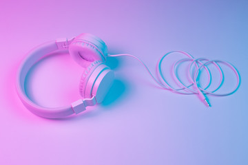 Retro 90s style photo of white stylish wireless headphone in neon lights. Music concept.