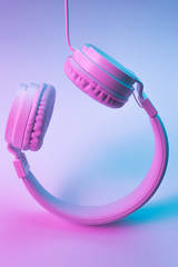 Retro 90s style photo of white stylish wireless headphone in neon lights. Music concept.