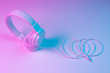 Retro 90s style photo of white stylish wireless headphone in neon lights. Music concept.