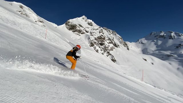 4K skiing footage in slow motion, sporty woman carving on ski slope on sunny winter vacation day in beautiful european alps  snow covered mountains with clear blue sky