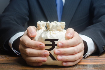 Businessman hugs indian rupee money bags. Granting financing business project or education. Trade,...