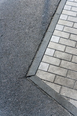 Texture of the border between asphalt and paving tiles