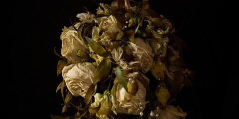 Wilted white roses in a vase in the dimness of the room