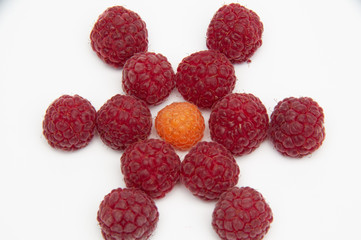Star from red and one of yellow in centre raspberries, photo from above on a white background