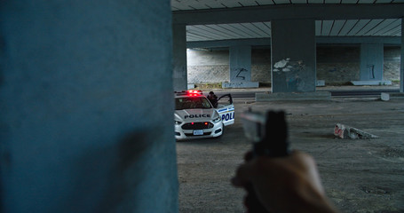 Shootout between police and criminals. Close-up dangerous offender shooting at police car and officers. Cops hiding behind the patrol car and fighting back. © Fractal Pictures