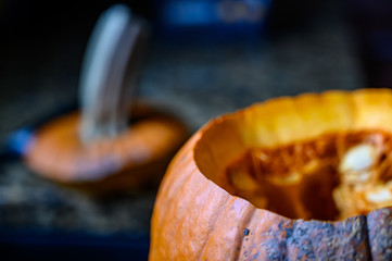 Open carved pumpkin with top and stem in the background