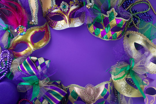 A group of Mardi Gras mask making a frame with copy space on a purple background