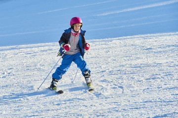 Fototapeta na wymiar Child skiing in the mountains. Toddler kid in colorful suit and safety helmet learning to ski. Winter sport for family with young children.