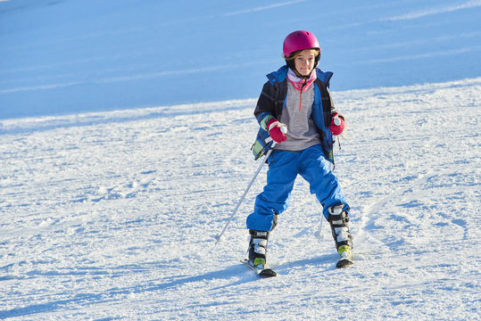 Child skiing in the mountains. Toddler kid in colorful suit and safety helmet learning to ski. Winter sport for family with young children.