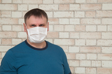 Coronavirus.A masked man against a brick wall.