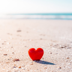 Romantic symbol of red heart on the sand beach