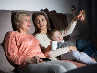Woman with her mother and son are watching film in time evening rest