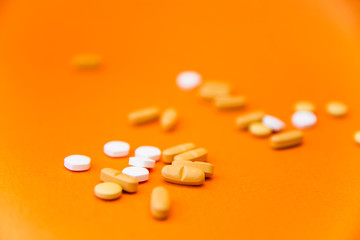 Health concept. Various pills isolated over the orange background. Selective focus. Close up