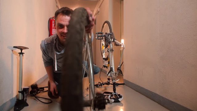 A man repairs a bicycle and lets the ring go to the camera.