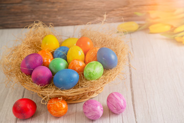 Obraz na płótnie Canvas Beautiful group Easter eggs in the spring of easter day, red eggs, blue, purple and yellow in Wooden basket on the table background wood