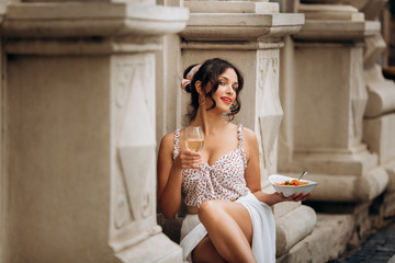 pretty woman with candid smile laughing sitting at summer cafe, dressed in white printed dress, fashionable street style