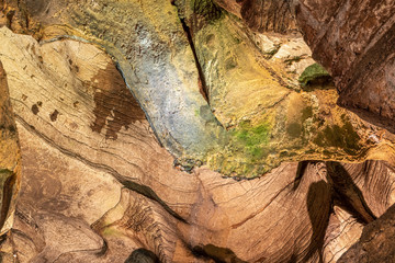 Obraz premium View inside the ancient cave with stone walls with additional lighting. Texture of a stone wall in a cave.